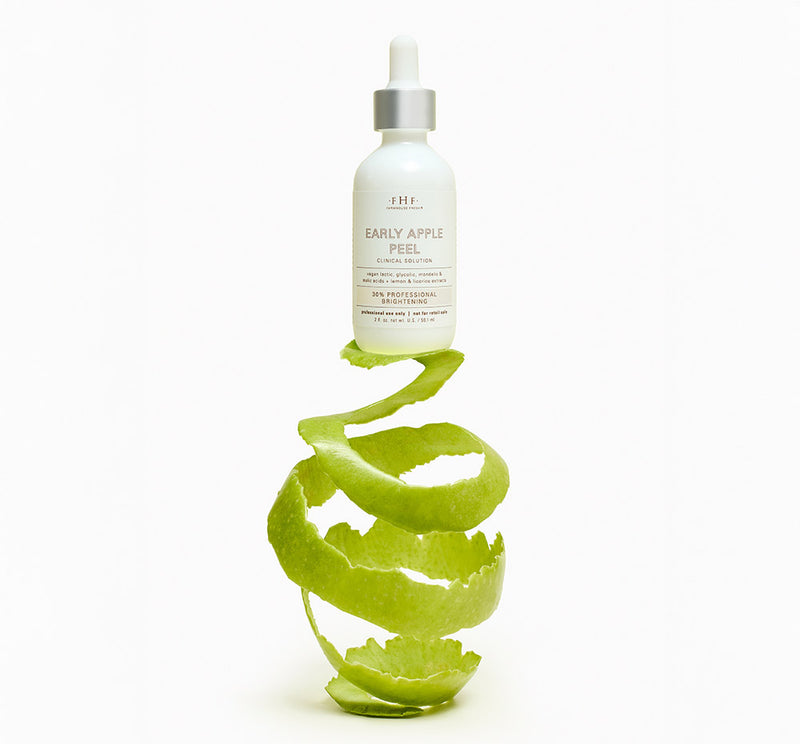 FHF Early Apple Peel bottle sitting on wrapped apple peel, on white background.