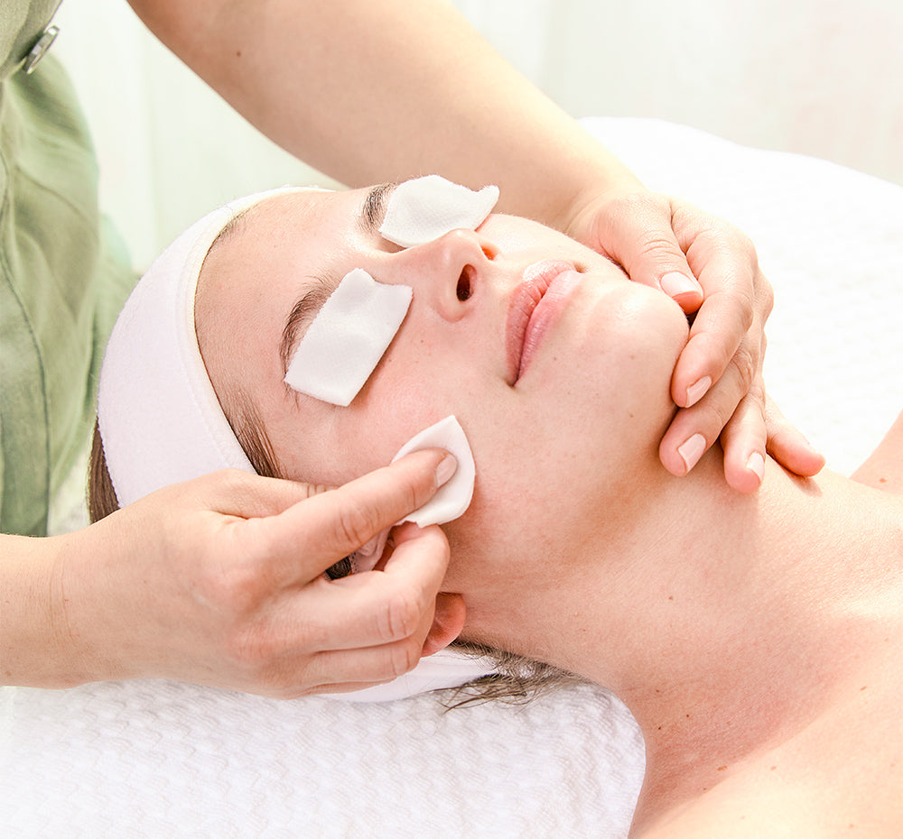Person receiving a FHF Professional Acid Peel facial treatment with white patches on their eyes.