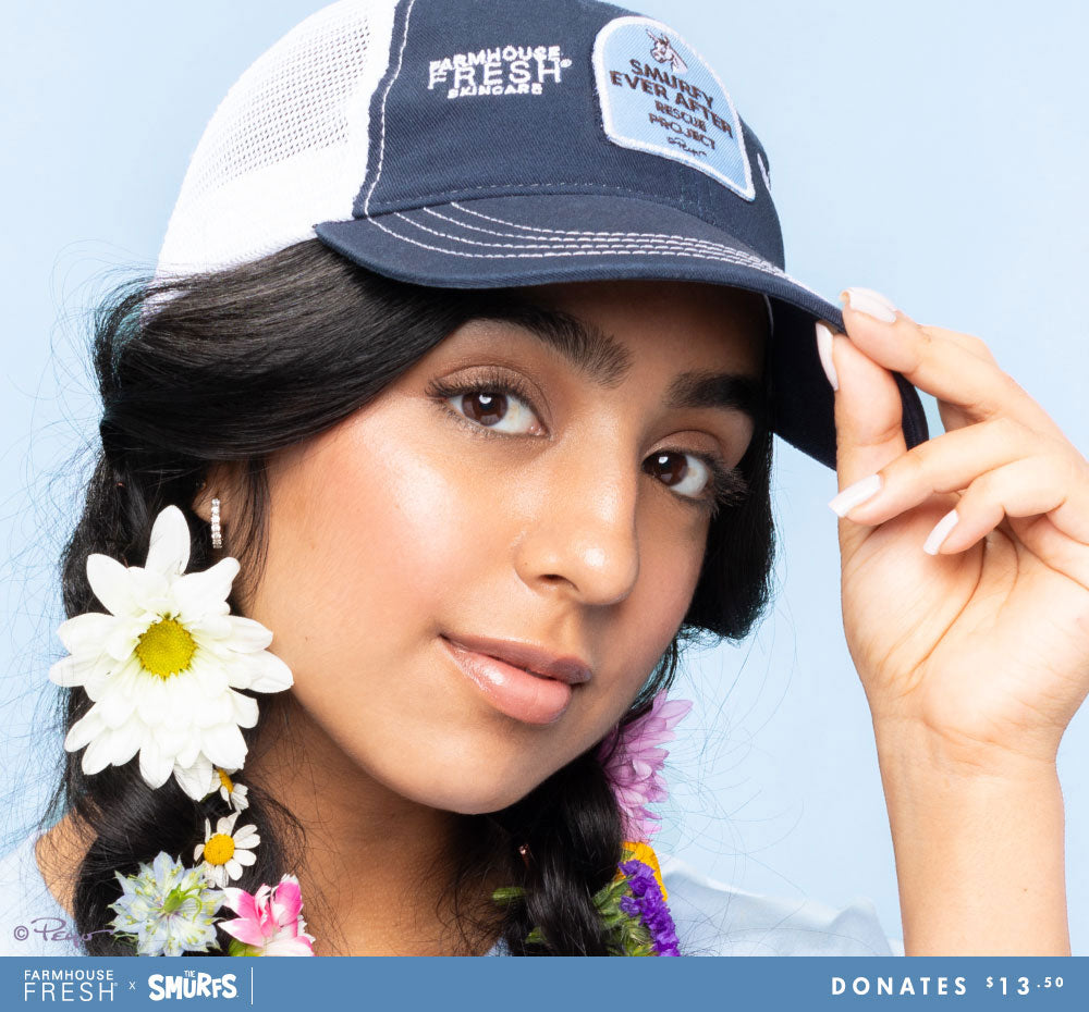 A woman wearing FarmHouse Fresh Smurfin' Cool Trucker Hat. All profits are donated to animal rescue initiatives around the country.