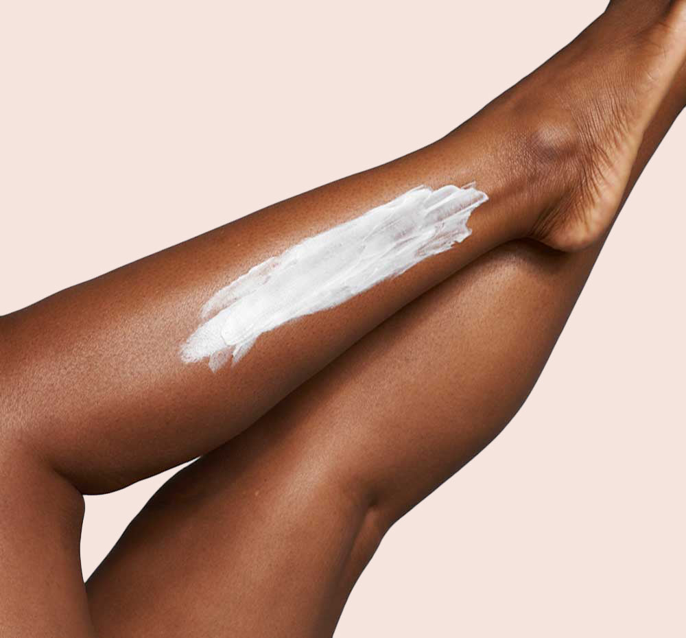 Woman’s legs with swipes of FarmHouse Fresh Sunshine Silk Shea Butter on them, demonstrating the thick texture of this body moisturizer.