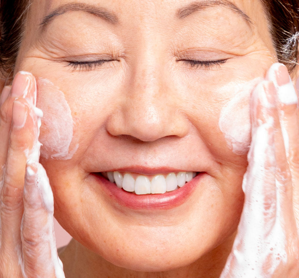 A woman using A woman holding up A bottle Three Milk Whipfoliant which has a herbal scent