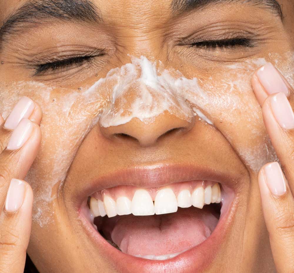 A woman exfoliating her face with FarmHouse Fresh Timescape Renewing Face Polish that delivers a smooth, glowing skin.