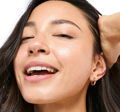 Close up of woman's smiling face wearing Tint-sational Sheer Skin-Perfecting Serum using shade Warm Sand