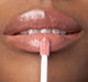 A woman is applying FarmHouse Fresh Vitamin Glaze Lip Gloss in Peach Peony color that restores dull  lips.