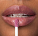 A woman is applying FarmHouse Fresh Vitamin Glaze Lip Gloss in Violet Orchid color that brings color to lips.