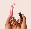 A hand holding FarmHouse Fresh Vitamin Glaze Oil Infused Lip Gloss in Sheer Pink color.