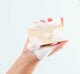 A hand holding all-natural Whoopie shea butter soap bar by FarmHouse Fresh, showing its rich lather.