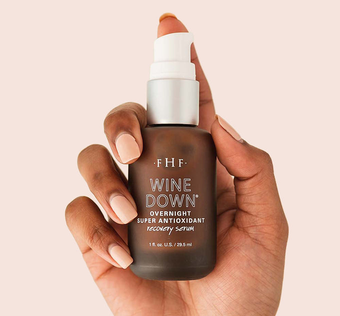 A hand holding Wine Down Overnight Super Antioxidant Recovery Serum by FarmHouse Fresh.