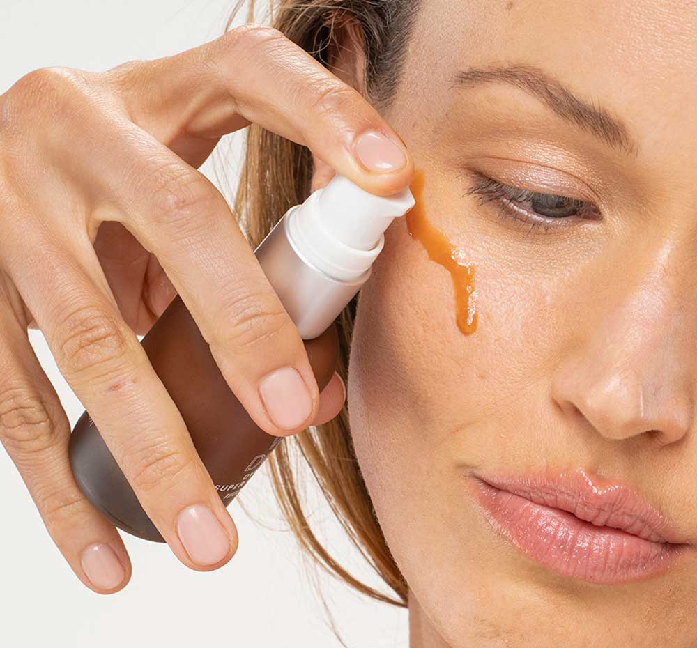 A woman is applying Wine Down Overnight Serum by FarmHouse Fresh that hydrates, fights wrinkles and makes pores look smaller.