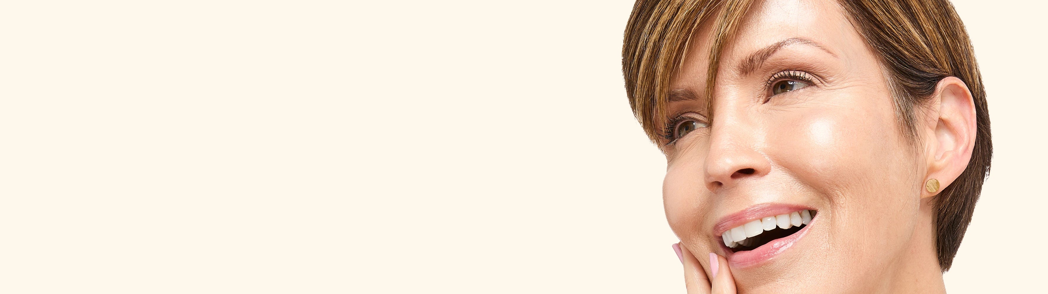 Woman with a bright smile on a beige background wearing Tint-sational Serum in shade Barely Beige