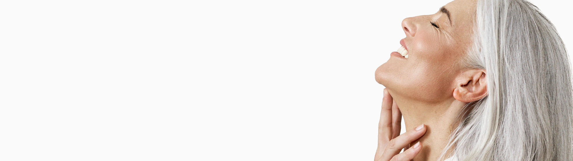 Woman with gray hair touching her face against a white background