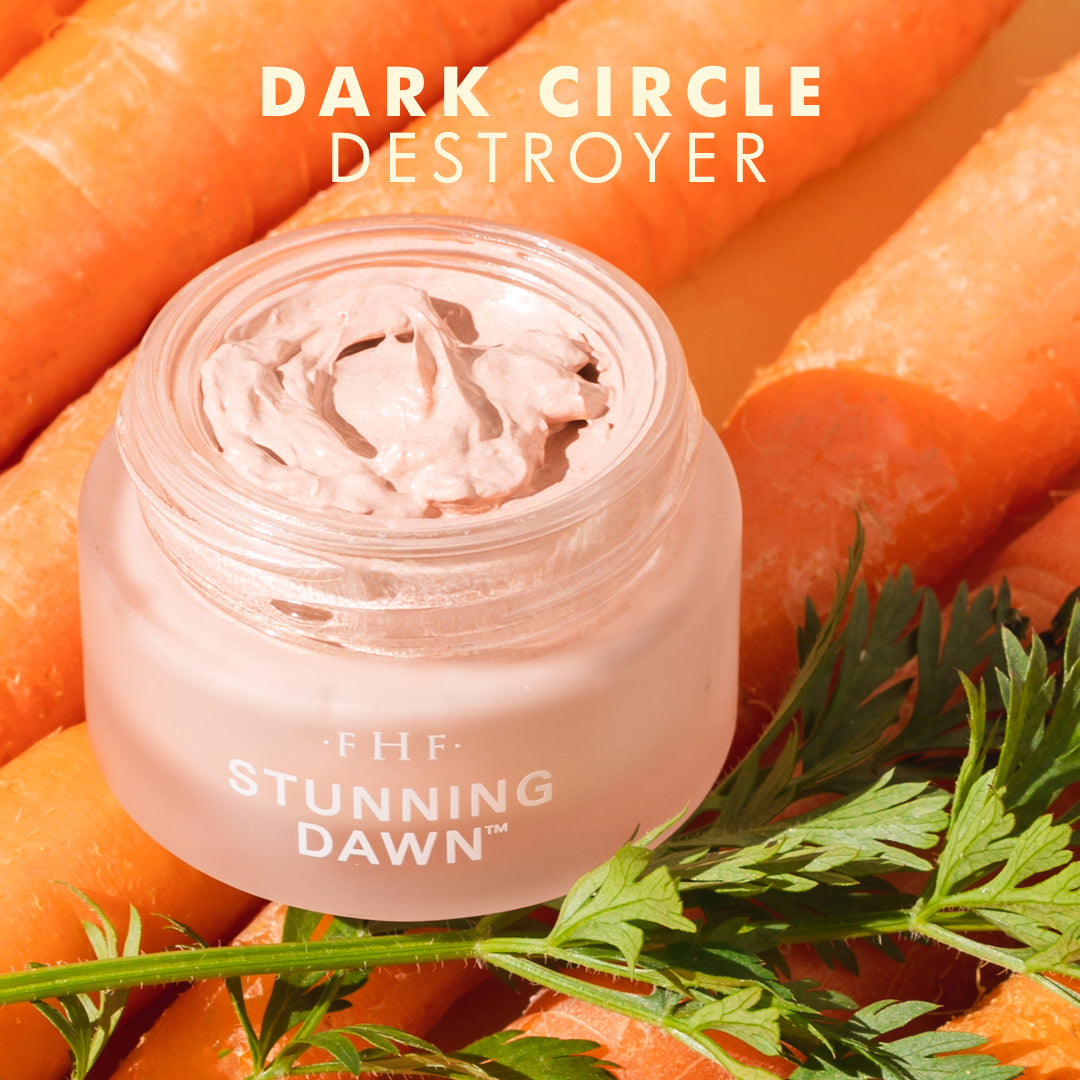 Jar of 'Stunning Dawn' eye cream with carrots in the background with text that says "Dark Circle Destroyer"