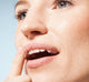 A close up of a woman's mouth with a finger on it, featuring Farmhouse Fresh's Blackberry Wine lip polish from Blackberry Lip Gift Basket with natural and exfoliating lip products.