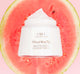 A jar of Farmhouse Fresh Blissed Moon Dip watermelon body lotion, a moisturizer for skin hydration, on top of a slice of watermelon.