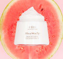 A jar of Farmhouse Fresh Blissed Moon Dip® watermelon body lotion, a moisturizer for skin hydration, on top of a slice of watermelon.