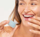 A woman is applying FarmHouse Fresh Bluephoria Lip Drench Jelly Sleep Mask to deeply moisturize her lips.