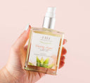 A woman holding a glistening bottle of Blushing Agave® Organic Body Oil by Farmhouse Fresh.