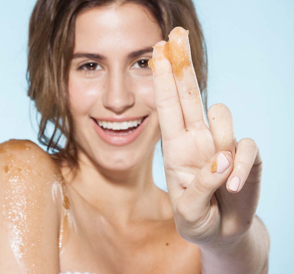 A woman shows her fingers with Bourbon Bubbler body scrub for silky smooth skin by Farmhouse Fresh.