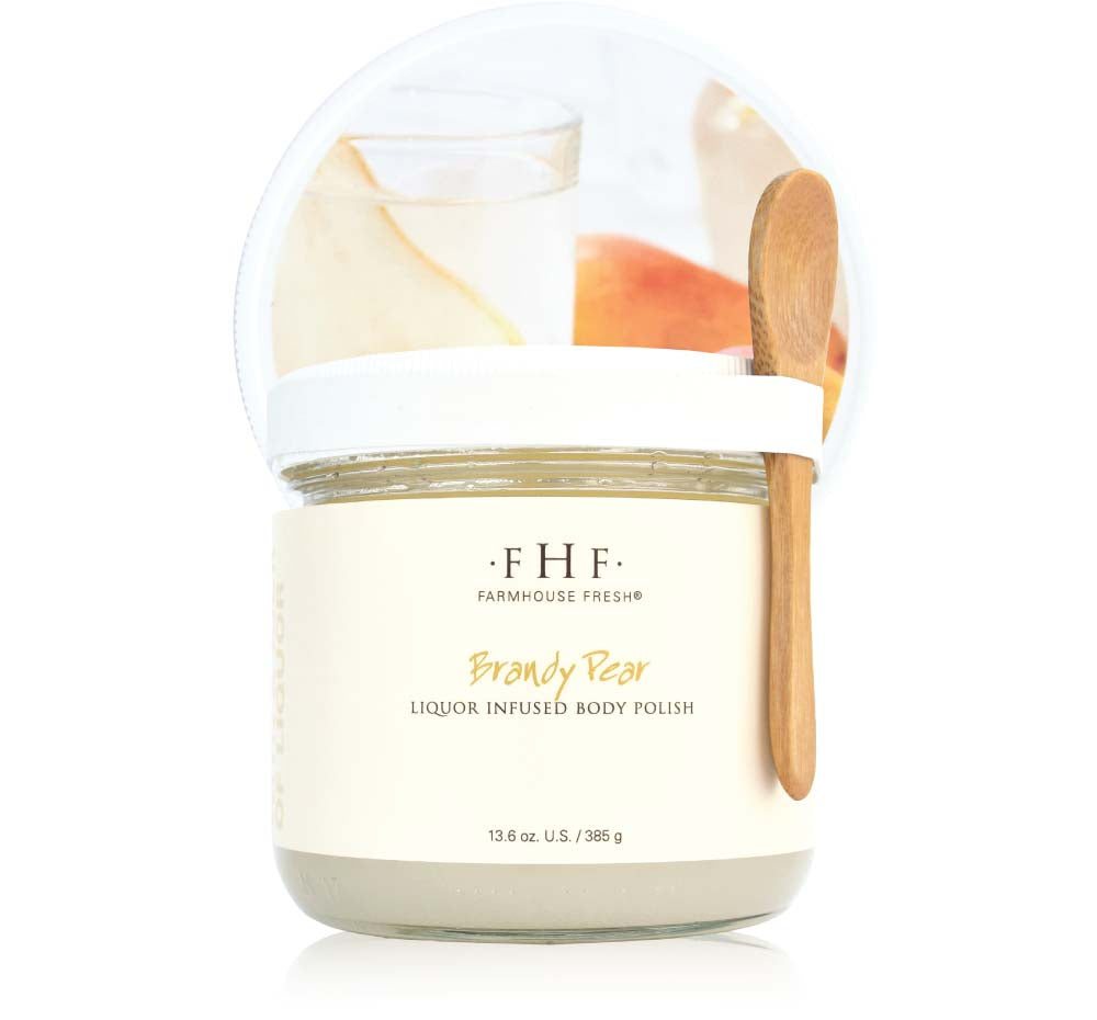 A jar of fruity Brandy Pear Liquor Infused Body Polish by FarmHouse Fresh with a wooden spoon.