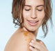 A woman is applying Farmhouse Fresh Butter Rum Scrub on her arm for exfoliation.