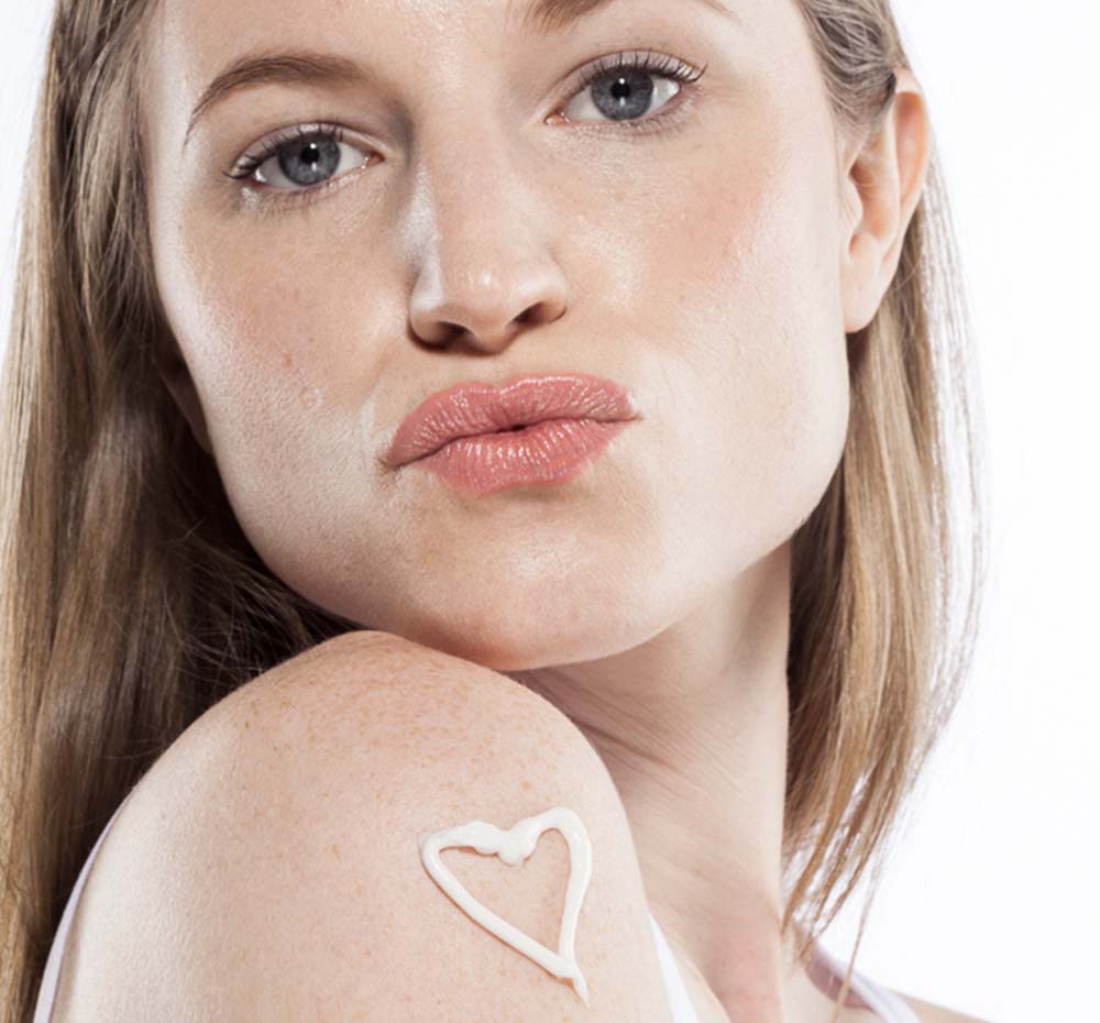 A woman with Buttermilk Lavender Steeped Milk Lotion by FarmHouse Fresh in shape of a heart on her arm.