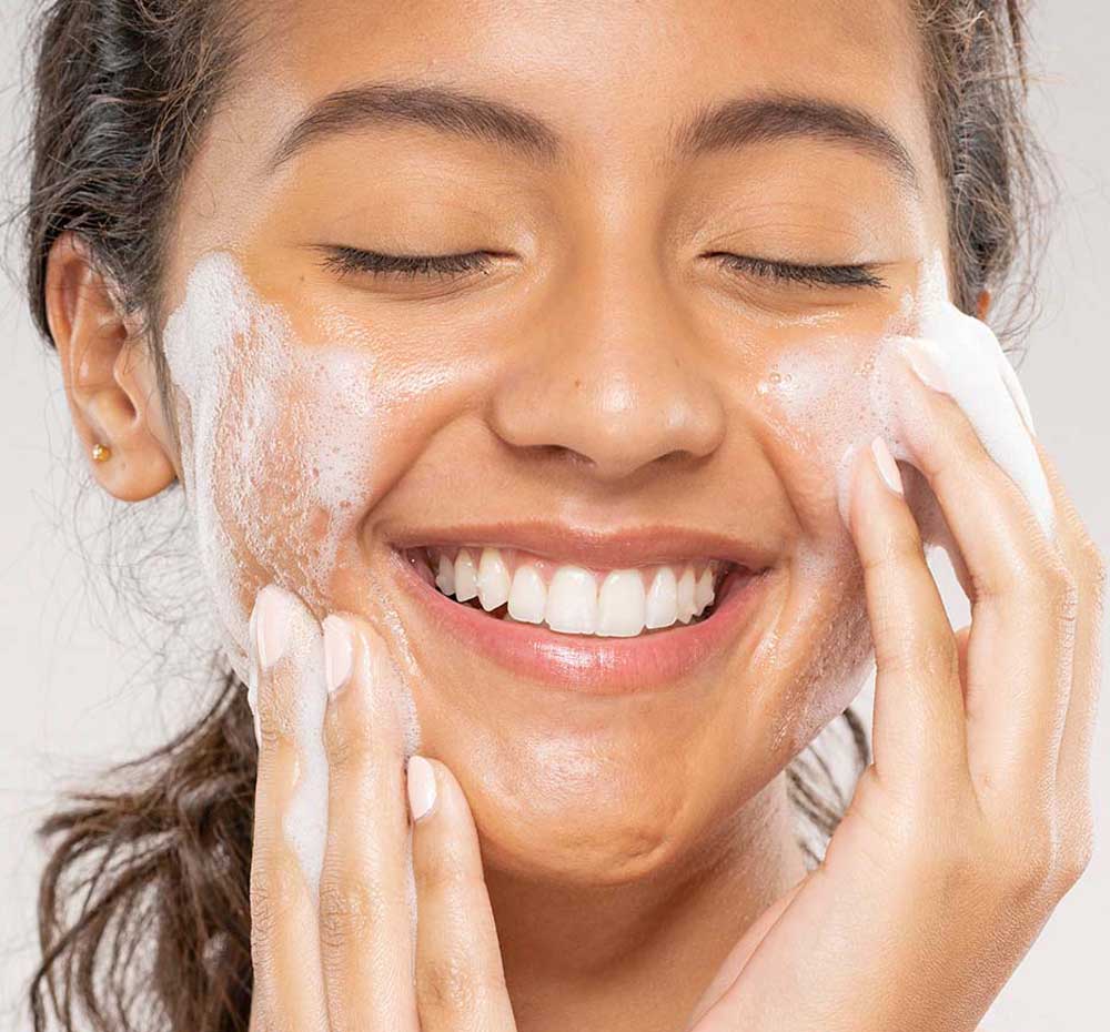 A woman is washing her face with FarmHouse Fresh C the Future Foam Facial Cleanser to refresh and clarify skin.