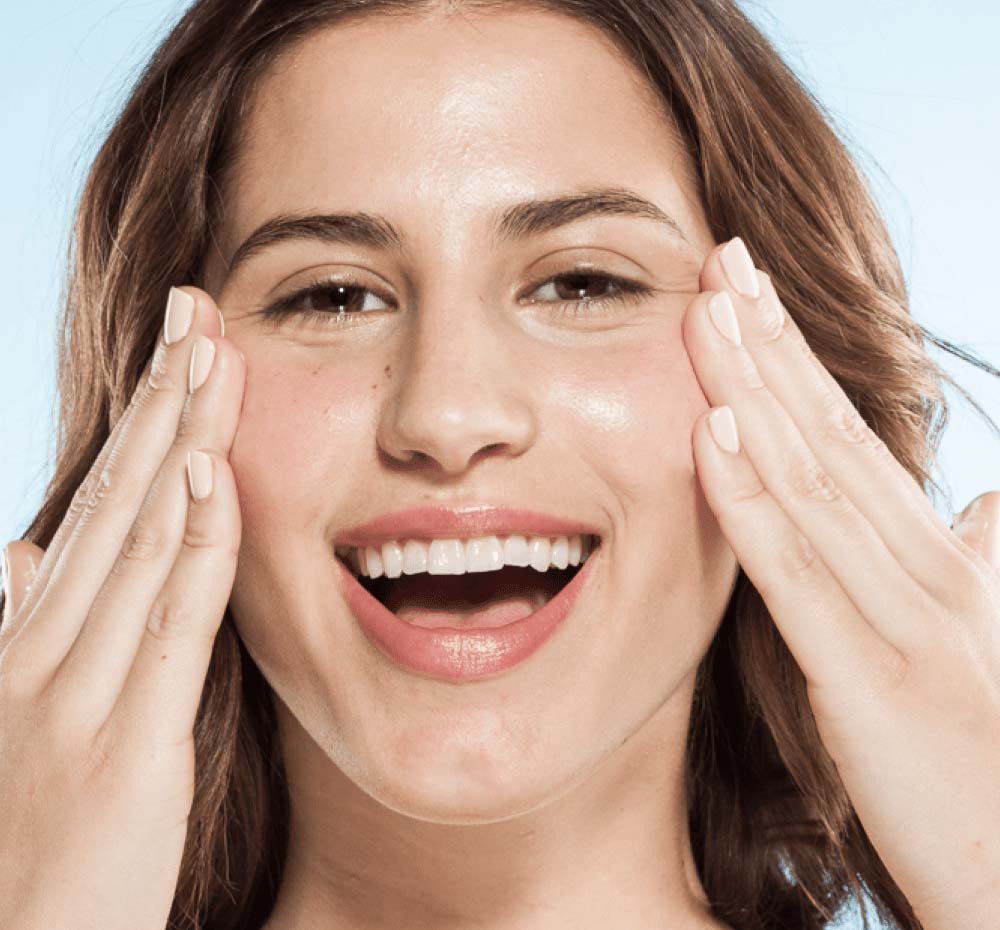 A woman is demonstrating her hydrated and plump complexion after using applying FarmHouse Fresh Chocolate Fig Vitamin Recovery Serum for dry skin.