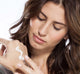 A woman is holding Citrine Beach® hydrating cream on her hand by Farmhouse Fresh.