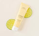 A tube of lightweight Citrine Beach® hand cream by Farmhouse Fresh on top of lime slices.