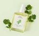 A bottle of refreshing Citrus Cilantro body oil on a green background.