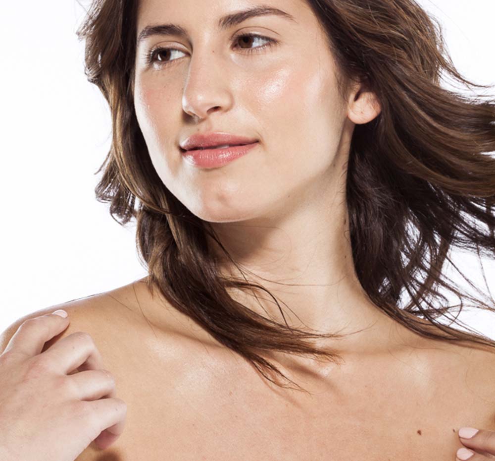 A woman showing her glistening skin after applying Farmhouse Fresh's Citrus Cilantro body oil for dry skin.