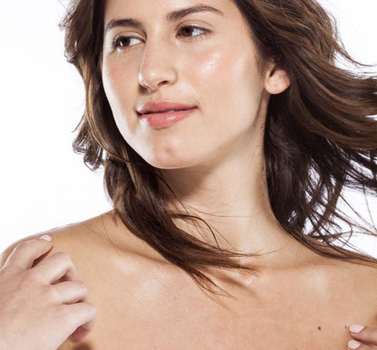 A woman showing her glistening skin after applying Farmhouse Fresh's Citrus Cilantro body oil for dry skin.