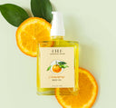 A bottle of light, citrusy Clementine Body Oil by FarmHouse Fresh on top of orange slices.