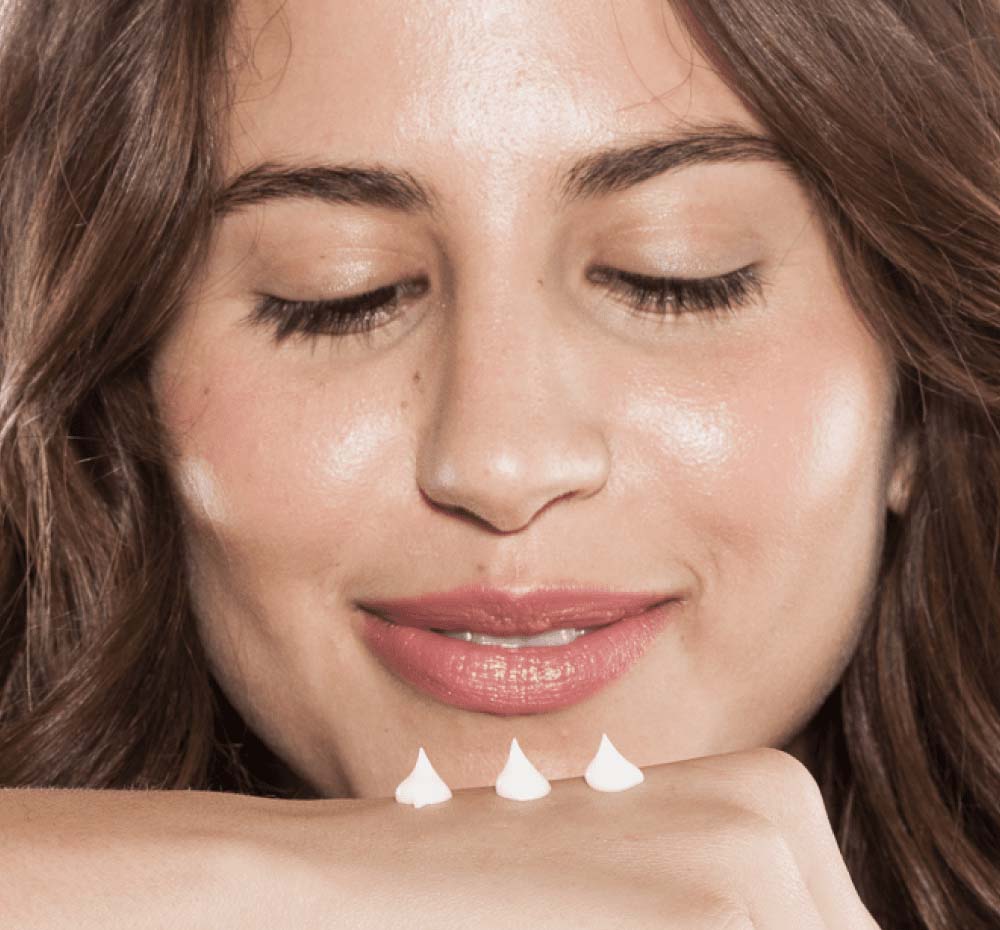 A woman is applying on her hand rich moisturizing Coconut Cream shea butter cream by FarmHouse Fresh to calm her dry skin.