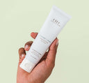 A woman's hand holding a tube of Farmhouse Fresh Coconut Cream Hand Cream enriched with shea butter to nourish and moisturize dry skin.