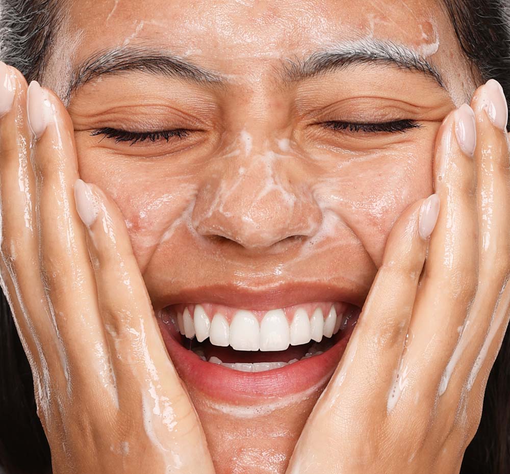 A woman is washing her face with FarmHouse Fresh Crisp Start Clarifying Face Wash that clears acne and breakouts while unclogging pores.