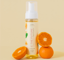 A bottle of FarmHouse Fresh C the Future Foam Facial Cleanser next to oranges that represent the natural ingredients full of vitamin C.