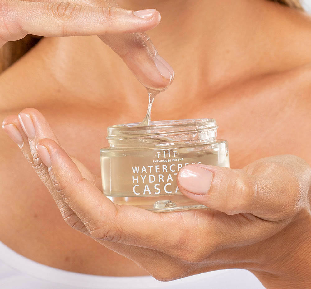 A woman is dipping her finger into a jar of FarmHouse Fresh Watercress Hydration Cascade, a rich cooling moisturizer for face.