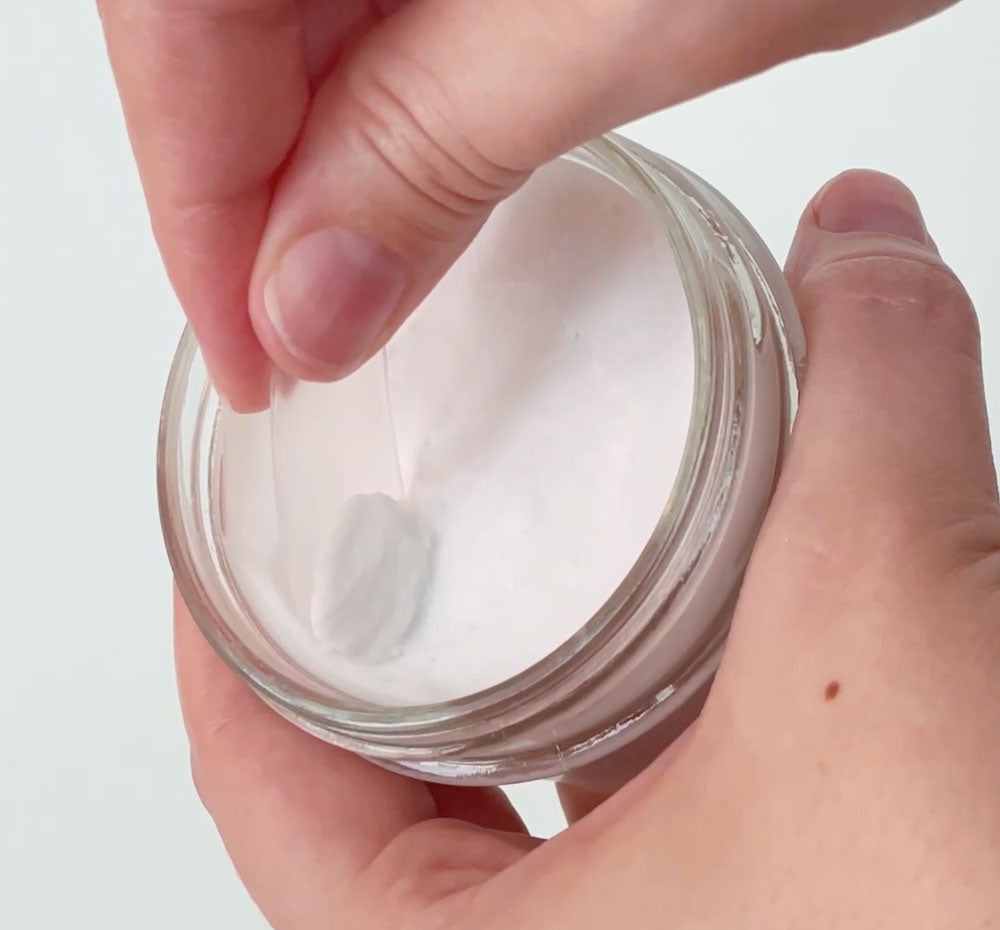 Person’s hands scooping a small amount of FarmHouse Fresh Enrich Mint Foot Rescue Mask with an applicator.