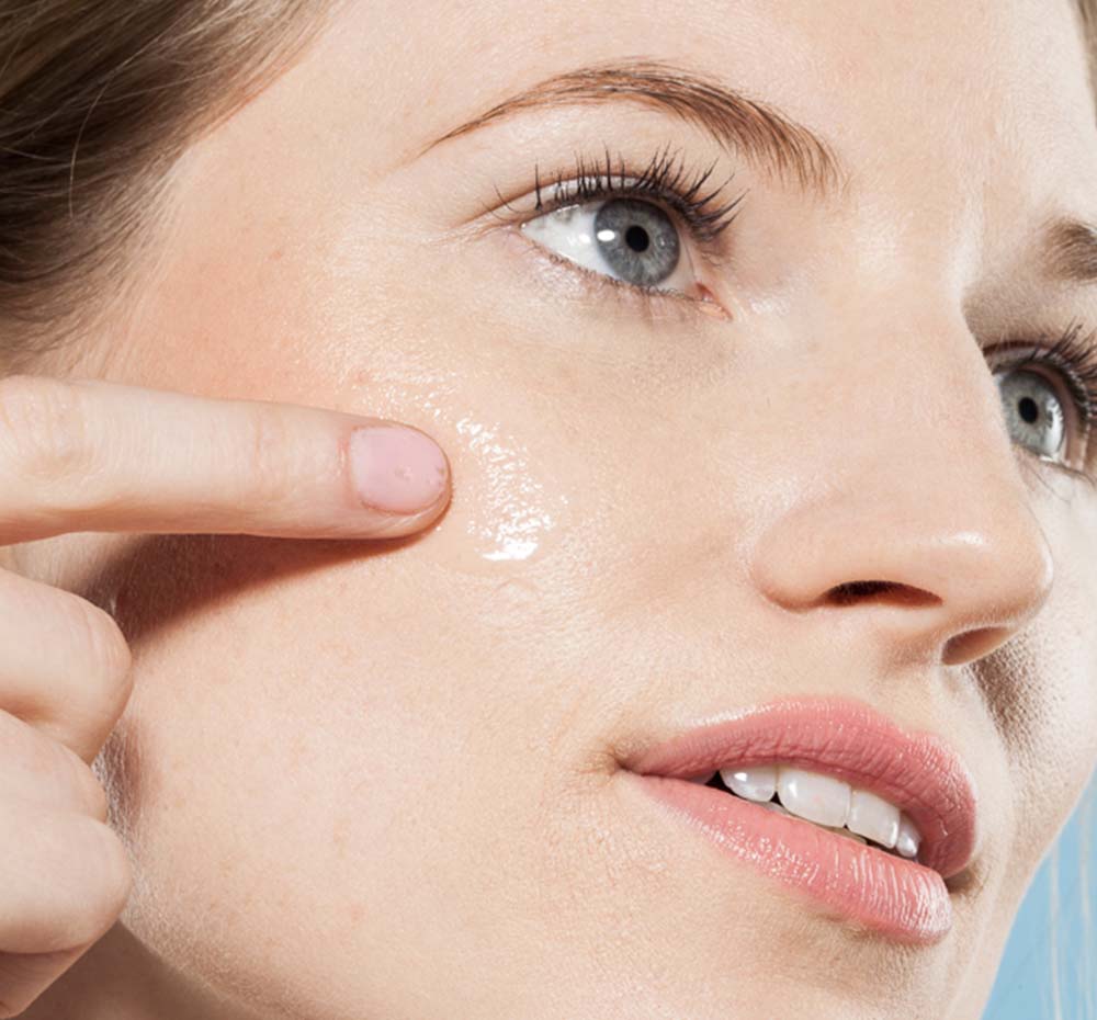 A woman is applying FarmHouse Fresh Eternal Light Face Illuminating Serum with vitamin C that is perfect for dull, sun damaged and aging skin.