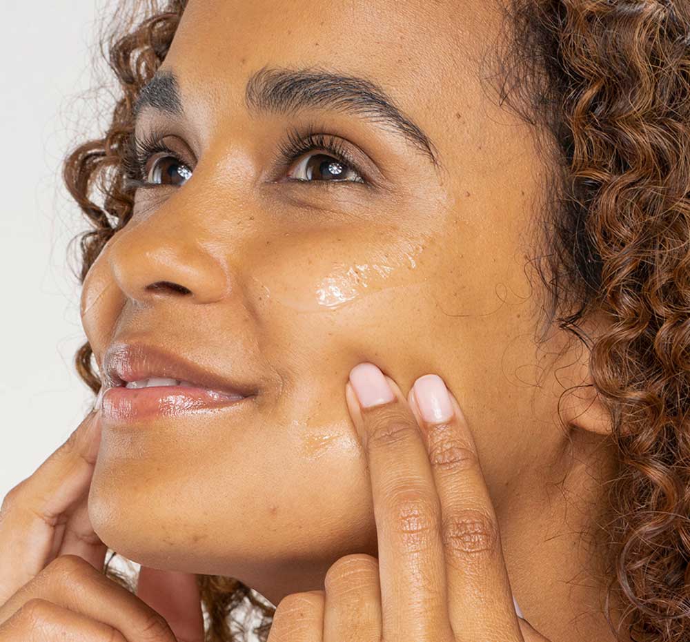 A woman is applying FarmHouse Fresh Eternal Light Vitamin C Face Serum for hyperpigmentation.