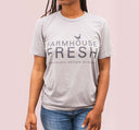 A woman wearing a FarmHouse Fresh Donation T-Shirt - Grey, supporting farm animals through donation.
