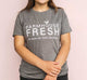 A woman wearing a FarmHouse Fresh Donation T-Shirt in grey color, supporting farm animals through donation.