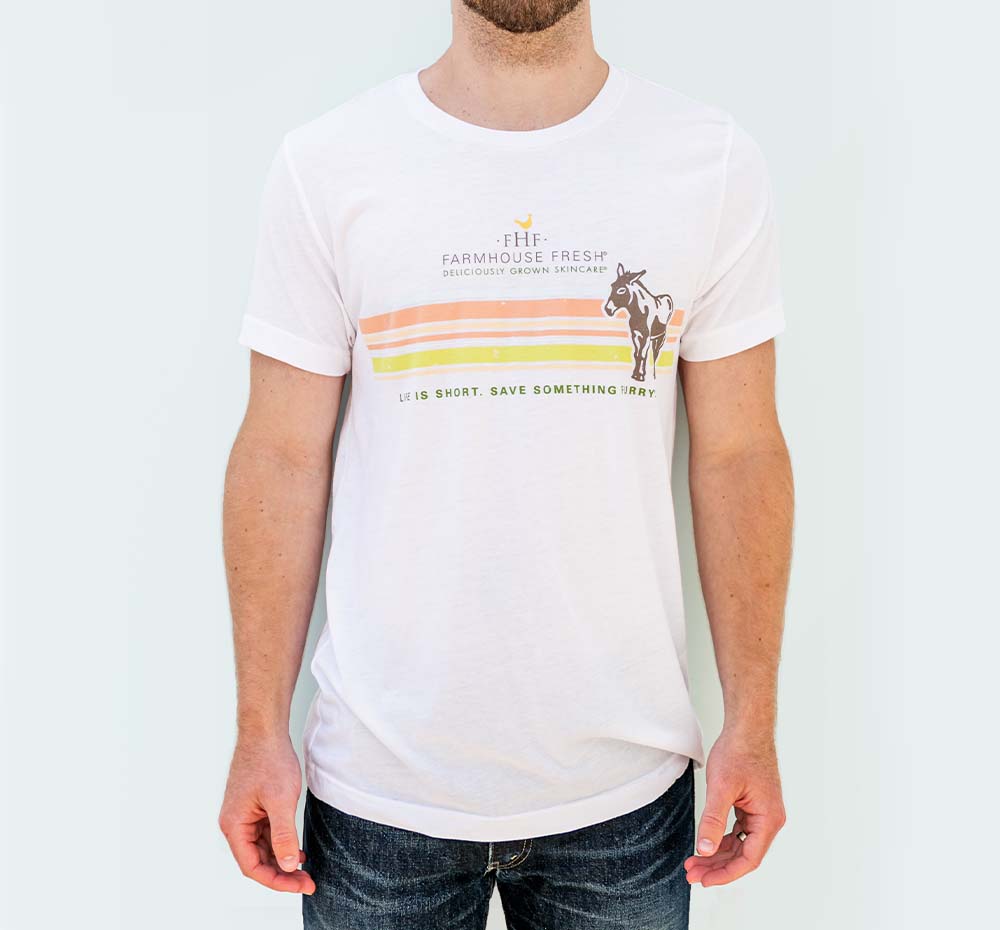 A man wearing white unisex FarmHouse Fresh T-Shirt that donates to farm animal sanctuary.