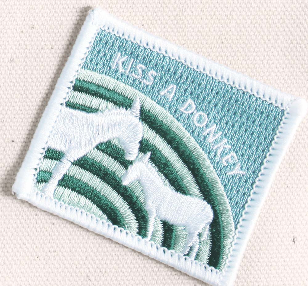 A patch with two donkeys that says Kiss a Donkey, which comes on a FarmHouse Fresh® Gifting Tote.