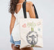 A woman is holding a FarmHouse Fresh® Gifting Tote with Goat Print and Patches, perfect as a farmers market's bag.
