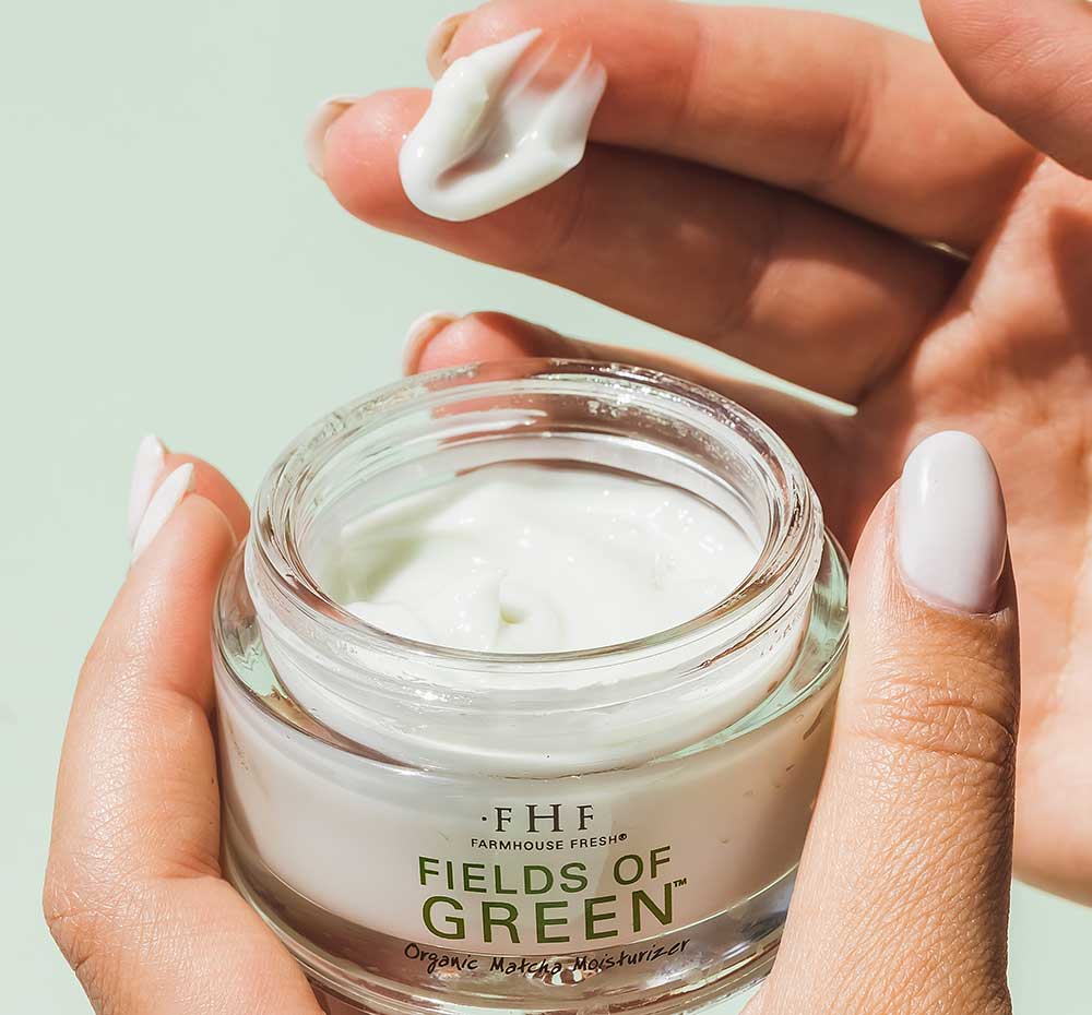 Person’s hands holding an opened jar of FarmHouse Fresh Fields of Green Organic Matcha Ultra-Soothing Face Moisturizer that calms rosacea flares.