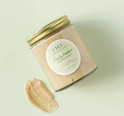 A jar and a texture smudge of Finely Awake face polish on a green background, showcasing the botanical, medium-sized exfoliating grains for smooth skin.