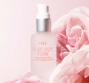A bottle of FarmHouse Fresh Flat Out Firm Hyaluronic Acid Peptide Firming Serum next to rose flowers that represent the organic rose hydrosol and other natural ingredients of this face serum.