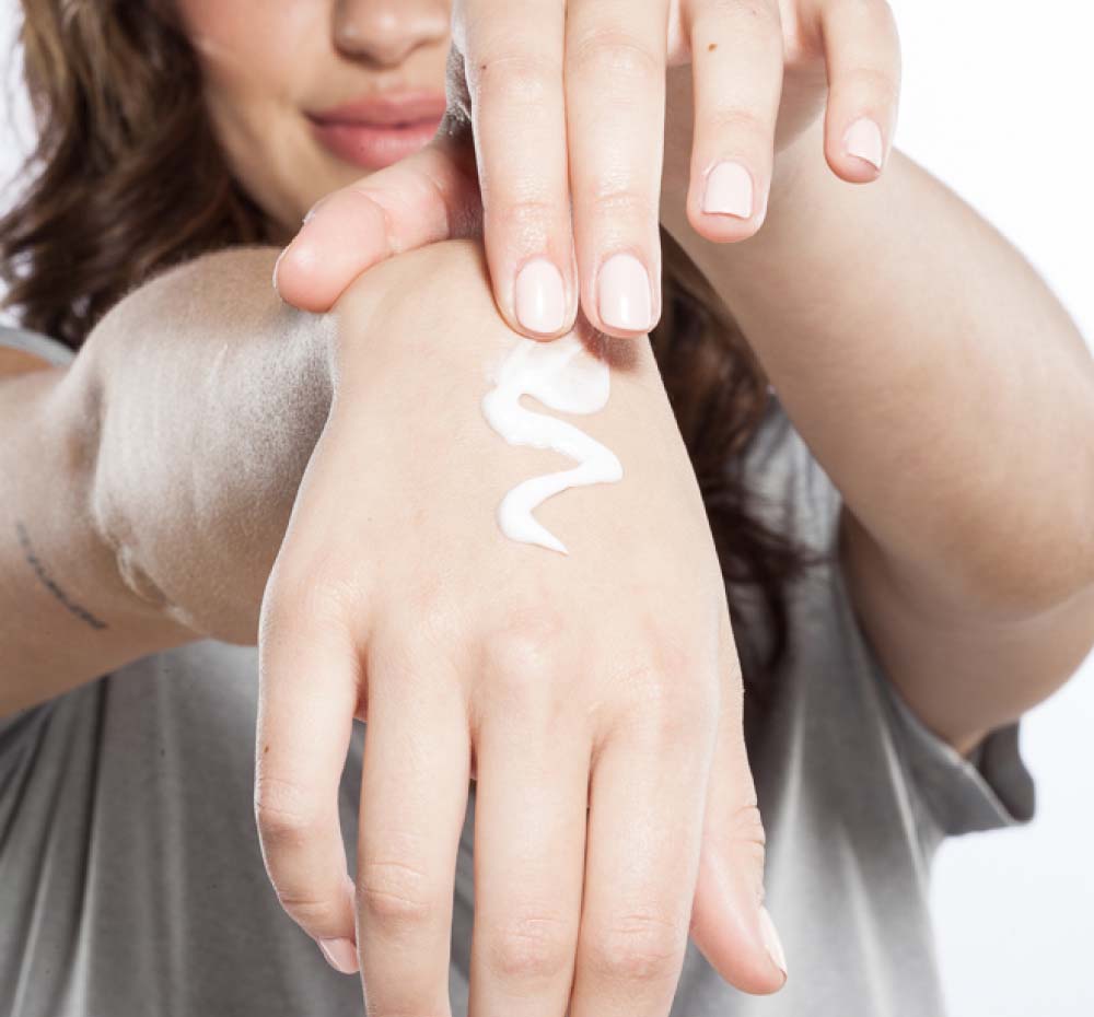 A woman is applying on her hand moisturizing Sugar Moon Dip Back To Youth Ageless Mousse by FarmHouse Fresh to calm her dry skin.